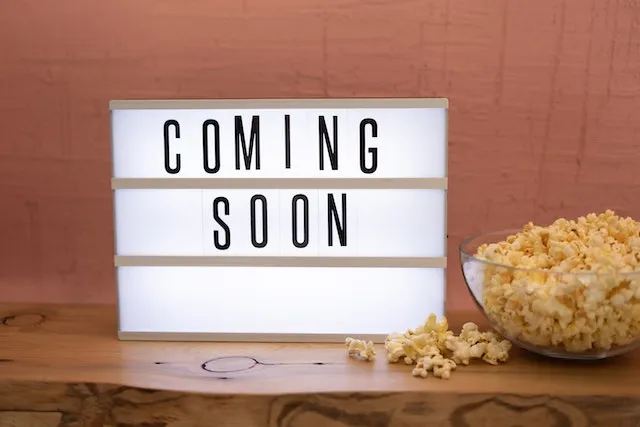 A light box standing on a table with a bowl of popcorn next to the light box the words Coming Soon are spelled out on the light box
